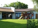 Das Außengelände der Kindertagesstätte in Schwalbach. Im Vordergrund sieht man das Spielgerüst auf einer großen grünen Wiese und im Hintergrund das Gebäude